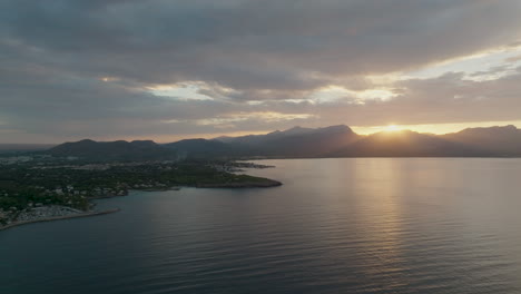 Vuelo-De-Drones-En-La-Costa-De-Mallorca-Con-Vistas-A-La-Zona-De-Bahia-De-Pollenca-Con-Espectacular-Puesta-De-Sol-Sobre-Las-Montañas