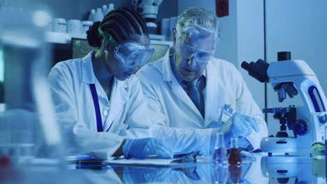 dos científicos de laboratorio vertiendo productos químicos