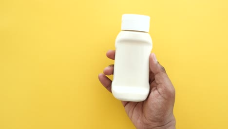 hand holding a white plastic bottle