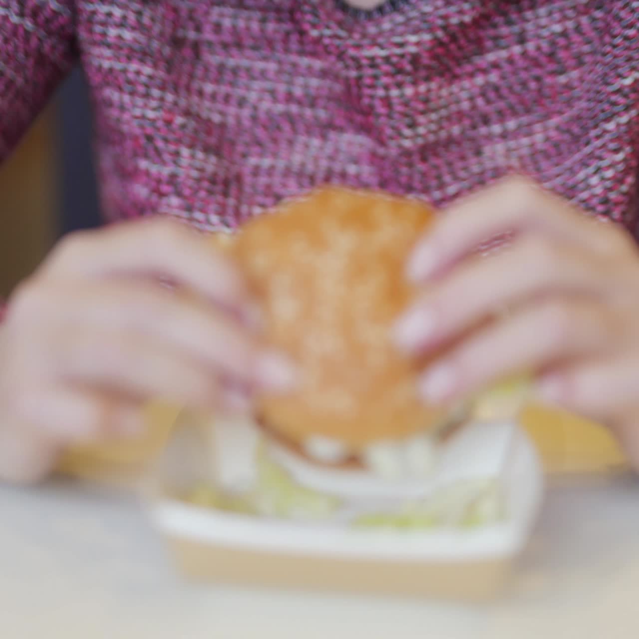 hungry young woman eating a big hamburger in a fast food restaurant