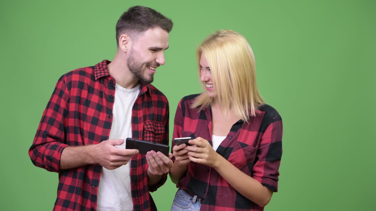 Young happy couple smiling while using phone together