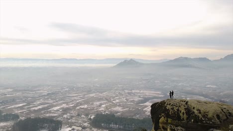 Zwei-Menschen-Stehen-Auf-Einem-Felsen-Mit-Blick-Auf-Die-Stadt