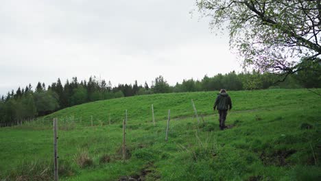 Lone-Person-Walking-In-Rural-Land-Fenced-With-Barbed-Wire