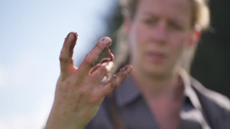 Female-farmer-inspecting-worm-in-hand-covered-in-soil,-vermiculture