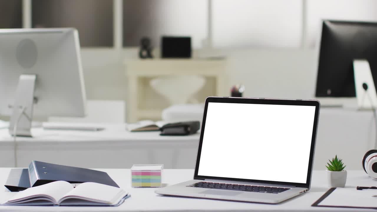 Laptop with copy space on screen on desk in empty modern office space, slow motion