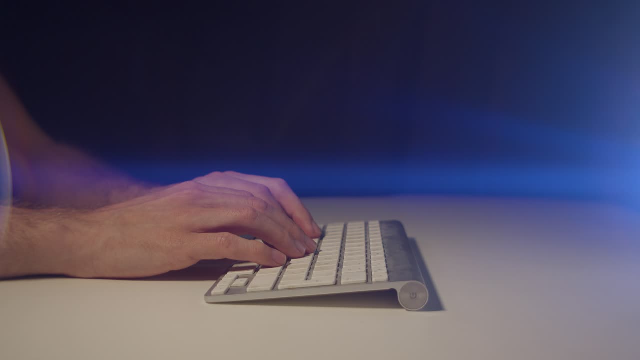 Working from home male hands typing slowly on a keyboard with cinematic lens flare pausing and waiting for a reply