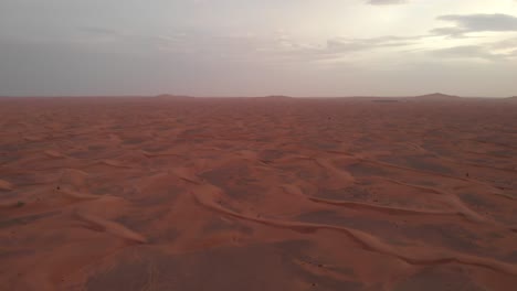 Panoramic-aerial-shot-of-arabian-red-desert-dunes-at-sunset-in-Dubai,-United-Arab-Emirates