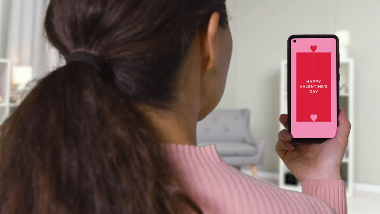 close up de la mujer en casa mirando el mensaje de feliz día de san valentín en el teléfono móvil