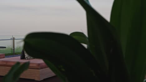 Leere-Sonnenliegen-Am-Pool-Auf-Der-Dachterrasse,-In-Der-Ferne-Ist-Der-Sonnenaufgang-Von-Dunst-Bedeckt