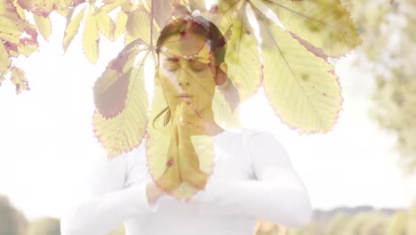 animation of leaves over caucasian woman practicing yoga and meditating