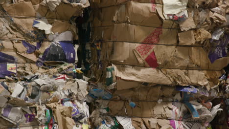 pressed cubes of waste paper, plastic bottles and cardboard at recycling plant, tilt up