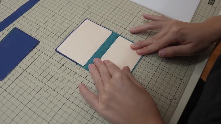 Craftsperson aligns two tone leather card cover halves together