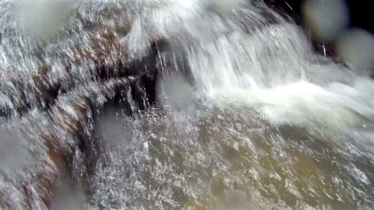 Water running over rocks and splashing the camera lens