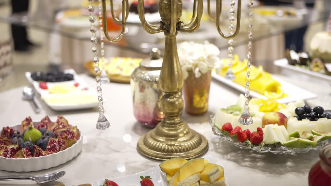 Mesa de bufé de boda con frutas frescas variadas y candelabros dorados decorativos