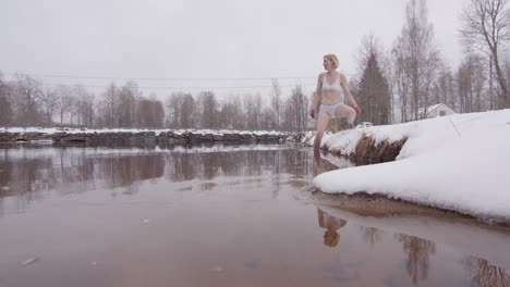 an experienced ice bathing woman in her 40s enters a cold lake