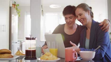 Kaukasisches-Lesbisches-Paar-Lächelt,-Während-Es-Zu-Hause-Einen-Videoanruf-Auf-Dem-Laptop-Führt