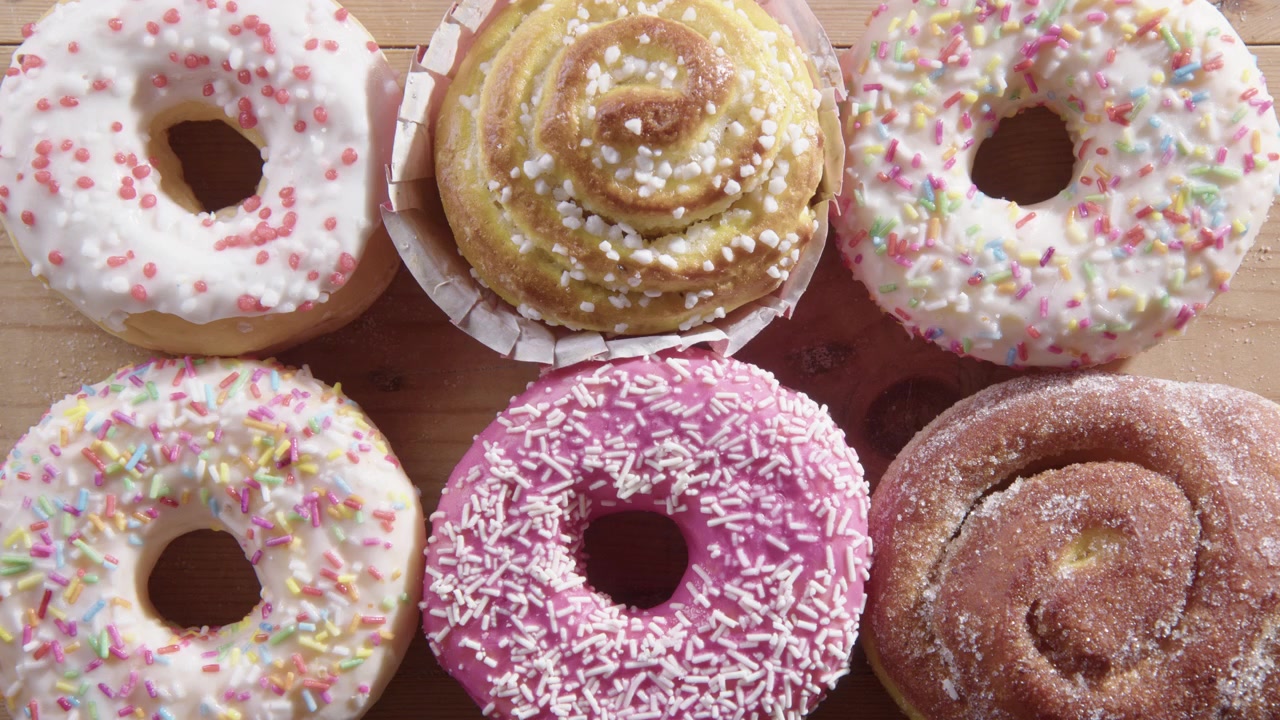 Vista de cima de meia dúzia de donuts sendo removidos um a um à mão
