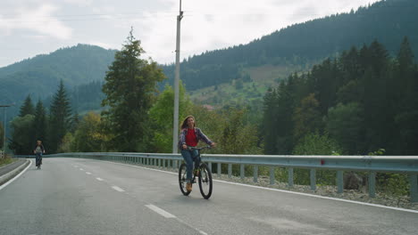 friends cycling forest road on sport bikes. carefree travelers enjoy mountains.