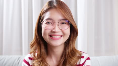 asian young woman with prescription glasses looking at the camera and smiling