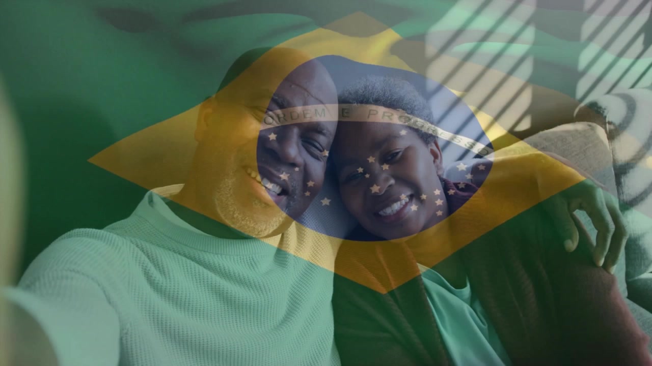 Modent par læner sig op ad sofaen og bruger smartphone, der viser et falmet brasiliansk flag-overlay til tech-annonce.