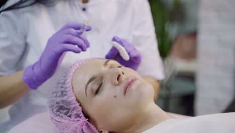 a beautiful woman is lying on a couch with at the cosmetologist on a mesotherapy procedure in the cosmetology. close-up