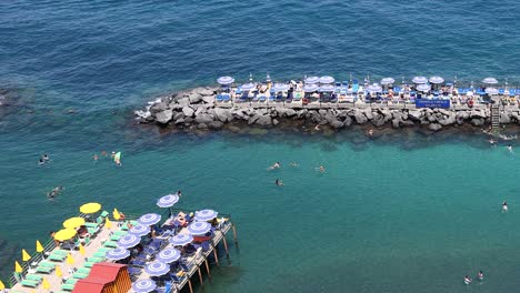 people swimming near a pier with umbrellas