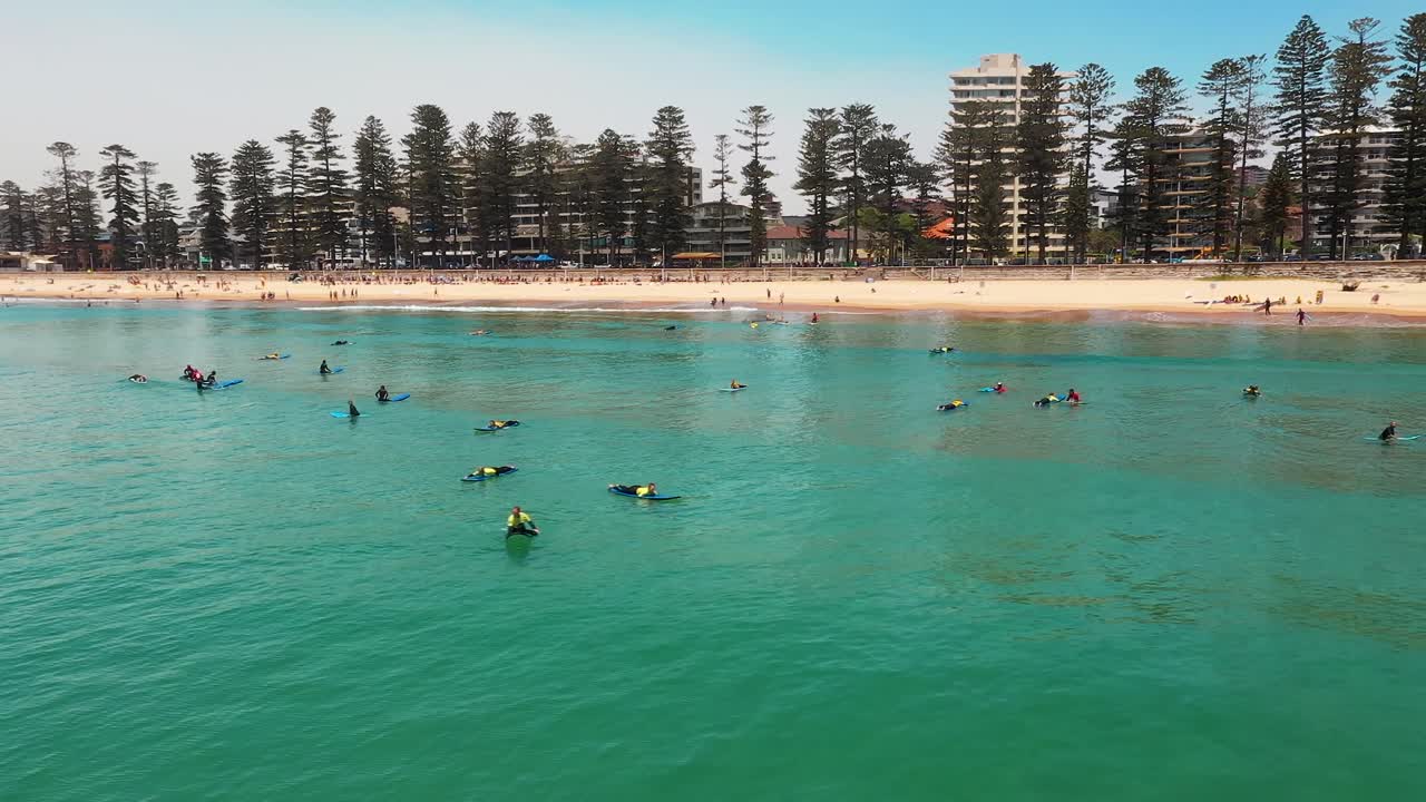 Aerial: Surfers out in the ocean on surfing beach on Sydney coast, Australia