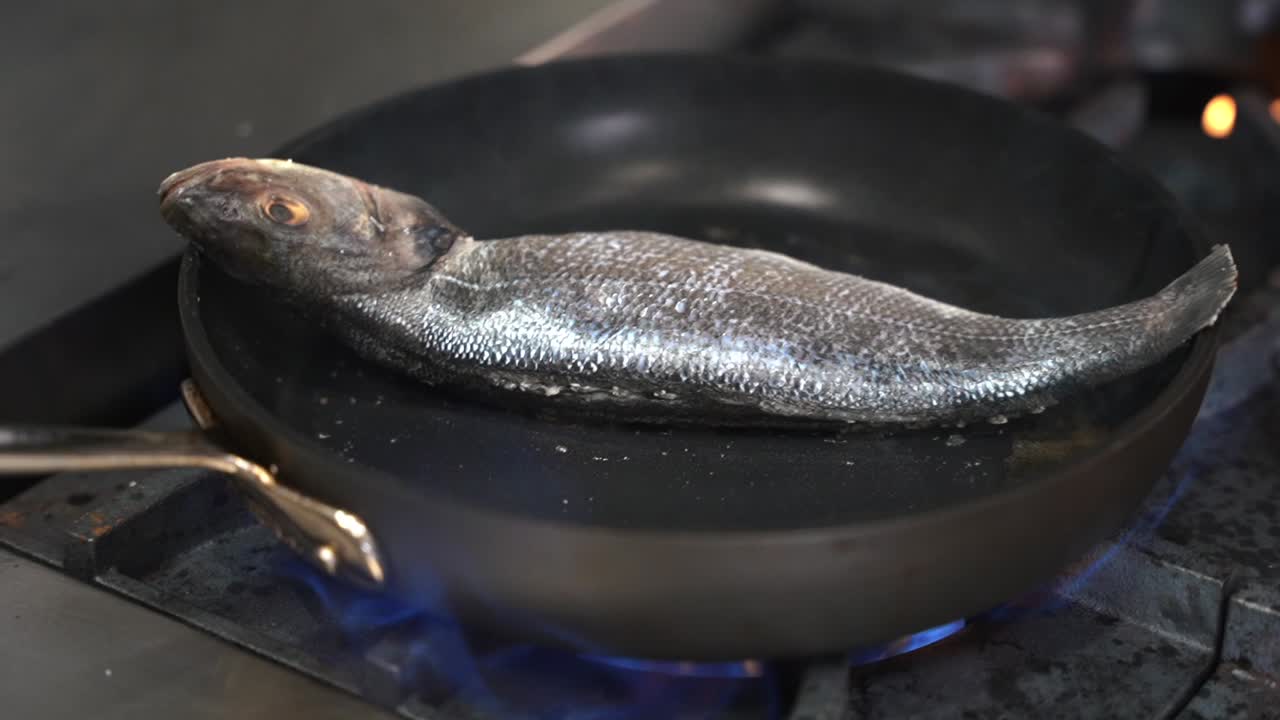 Fish frying in a pan without being moved. Smoke rising up and gas visible