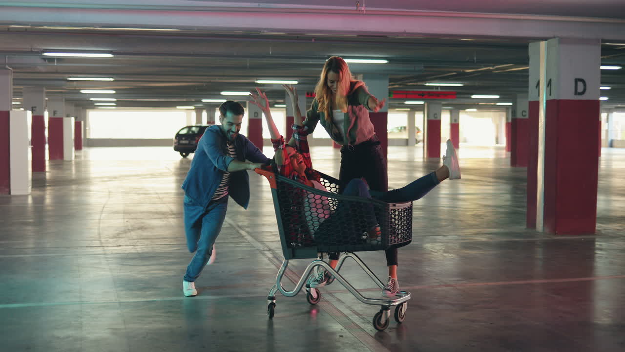 빈 주차장에서 트롤리에 그들을 운반하는 동안 두 여자와 재미 젊은 쾌활한 백인 남자