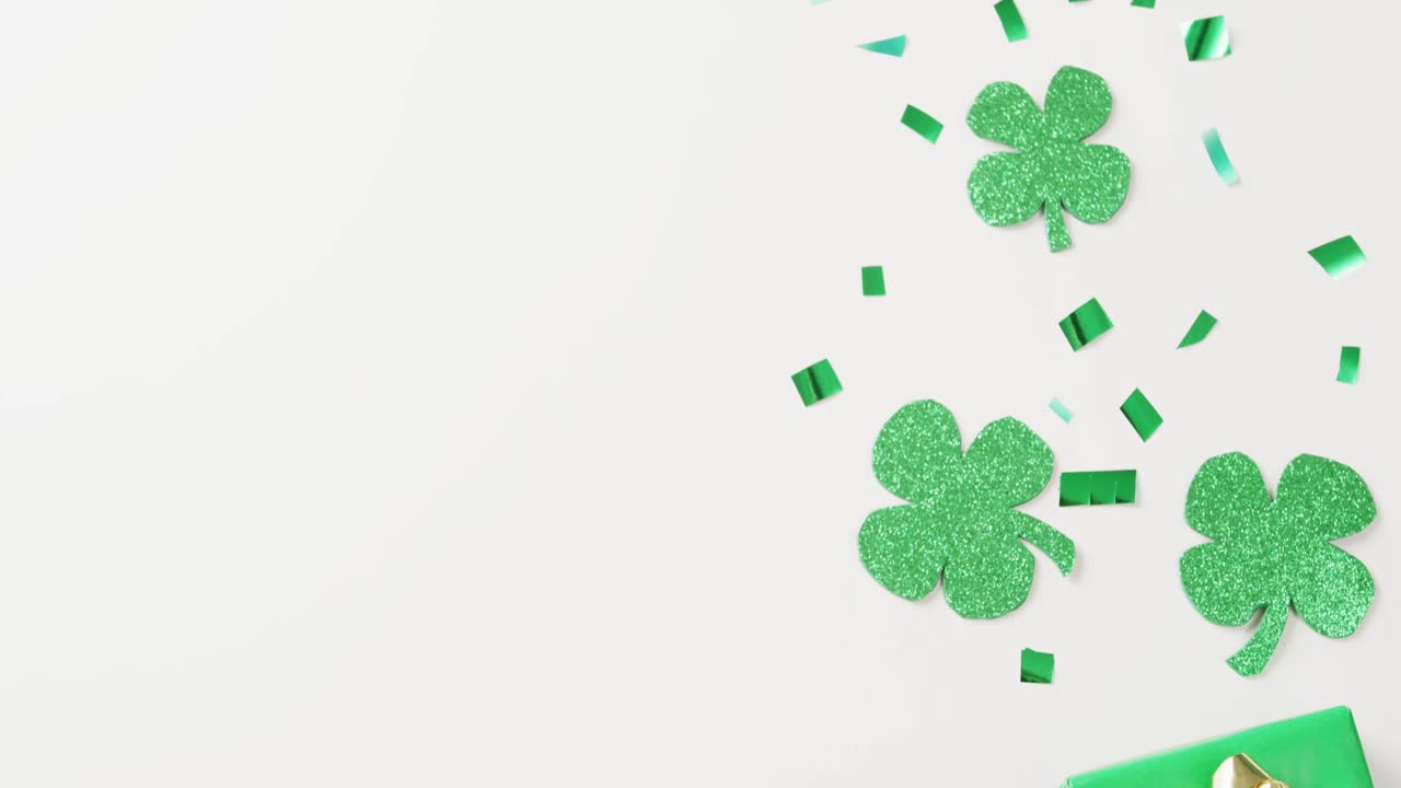 Video of st patrick's shamrock leaves and present with copy space on white background