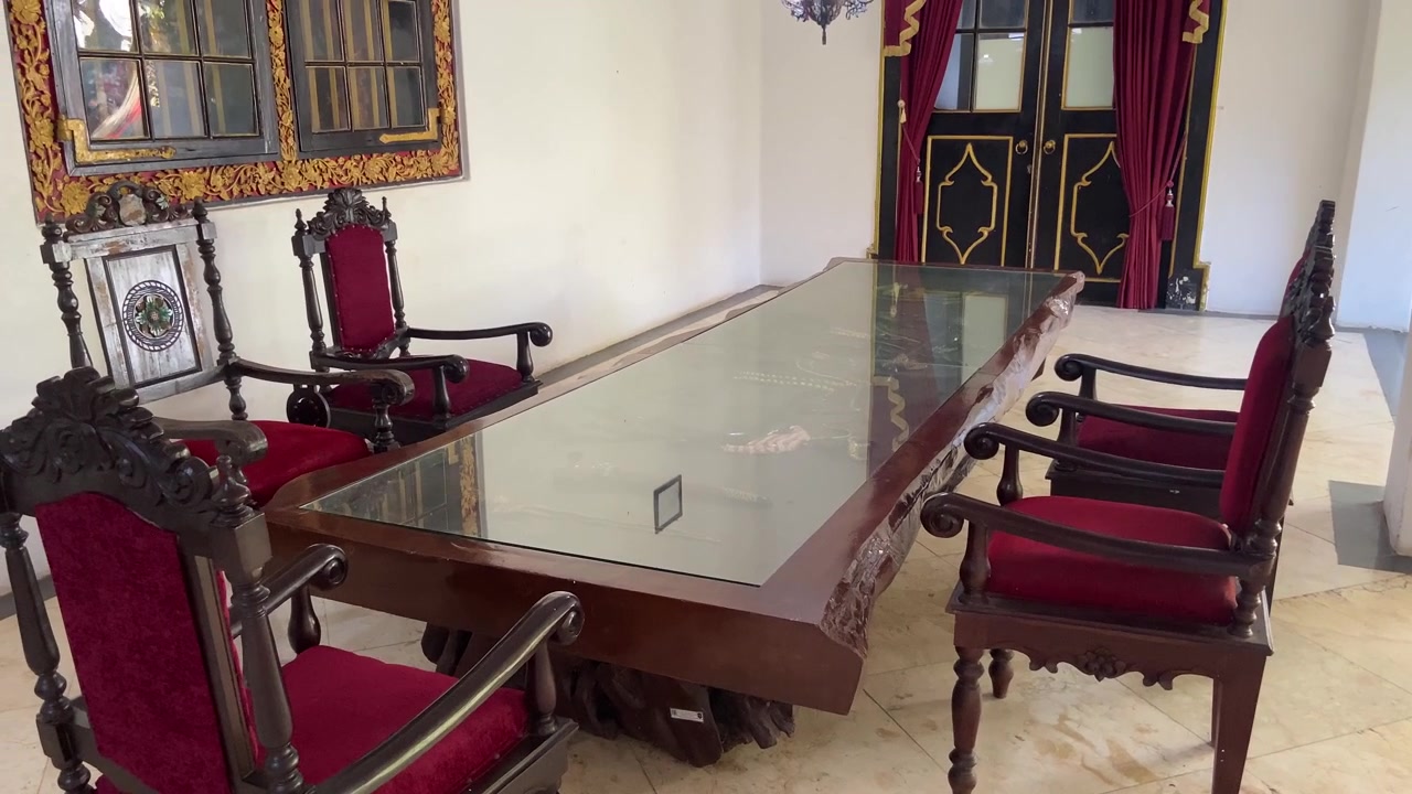 Lujosa mesa y sillas de madera ornamentadas con cojines de terciopelo rojo