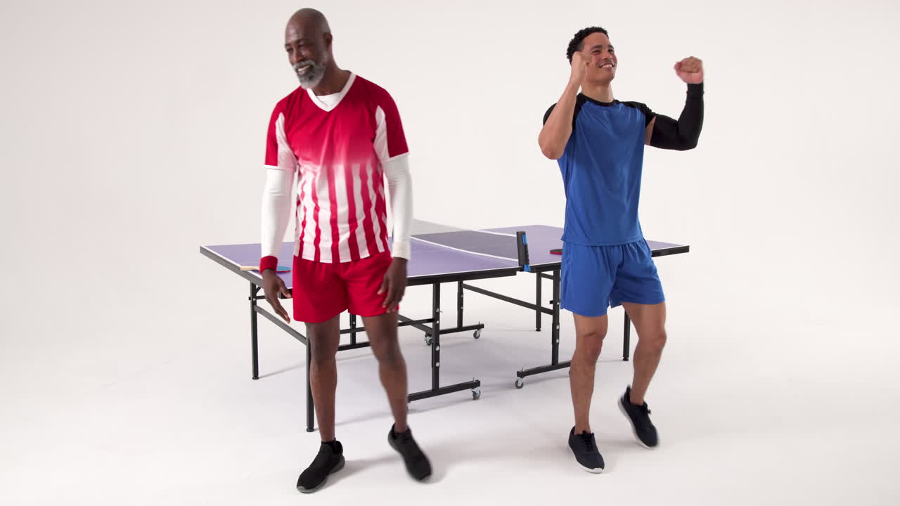 Playing table tennis, two men celebrating and enjoying game in studio