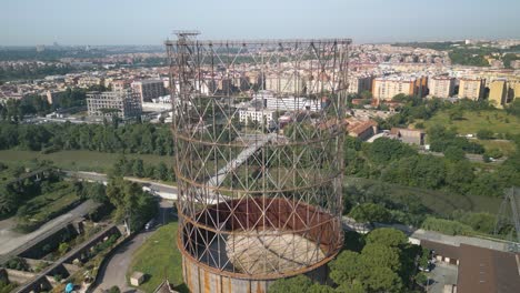 Aerial-drone-tilt-up-shot-over-an-old-iron-structure-symbol-of-the-Ostiense-district-of-Rome,-Italy-on-a-sunny-day