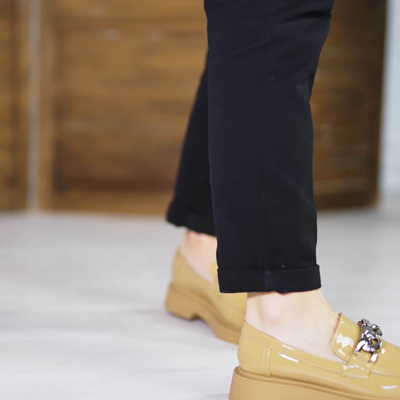 Beige comfortable shoes on a female model wearing black jeans. Demonstrating new loafers with silver chain decoration