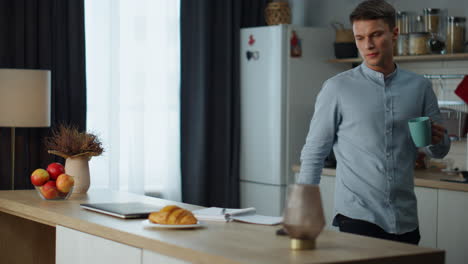 el hombre comienza a trabajar con una computadora portátil sentado en la cocina con café. freelancer comprueba el correo electrónico.
