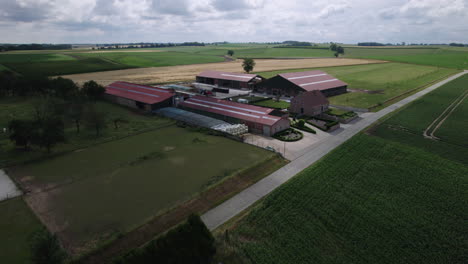 Drone-lowering-panning-shot-of-a-large-farming-complex-in-Belgium-on-a-cloudy-day