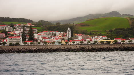 Small-local-town-with-orange-rooftops-located-on-the-rocky-coastline-of-the-Azores-Islands,-Atlantic-ocean,-Portugal