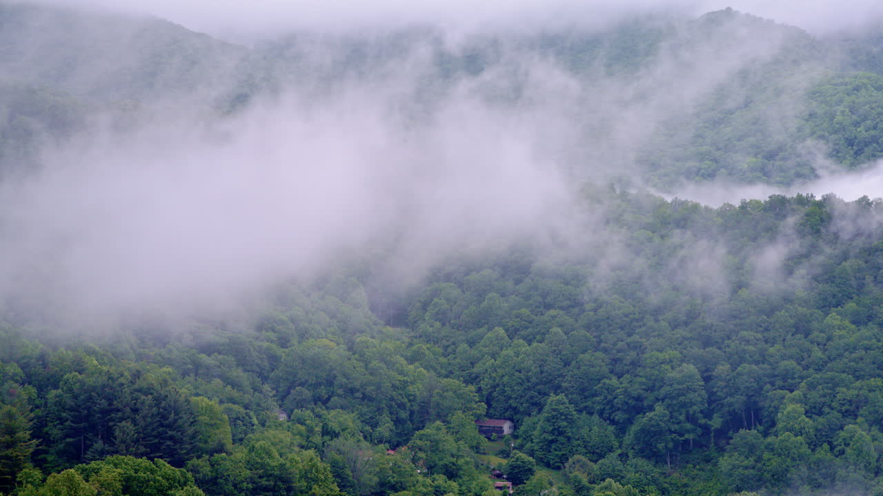 Aerial view gliding over a quiet, fog-covered valley at sunrise