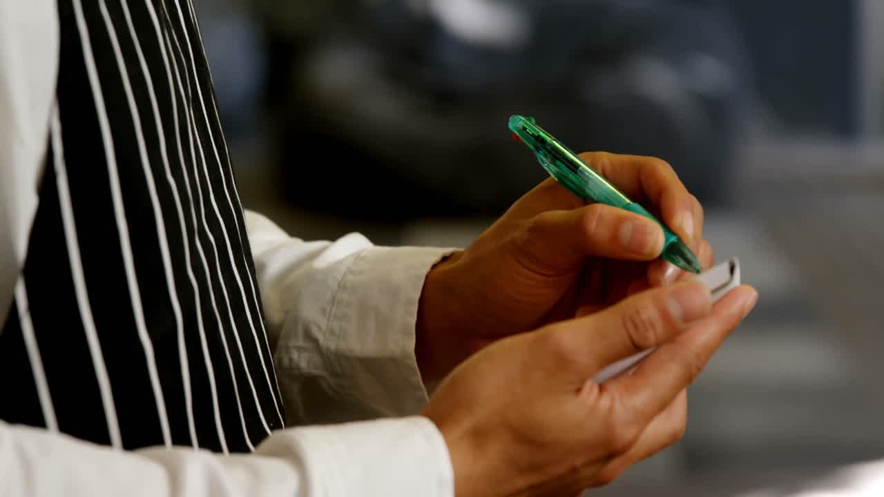 Mid section of waiter writing order in notepad 4k
