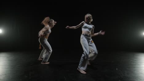 een groep professionele dansers oefent capoeira in het donker tegen een schijnwerper op een zwarte achtergrond van een afro-braziliaanse vechtkunst die elementen van de dans combineert.