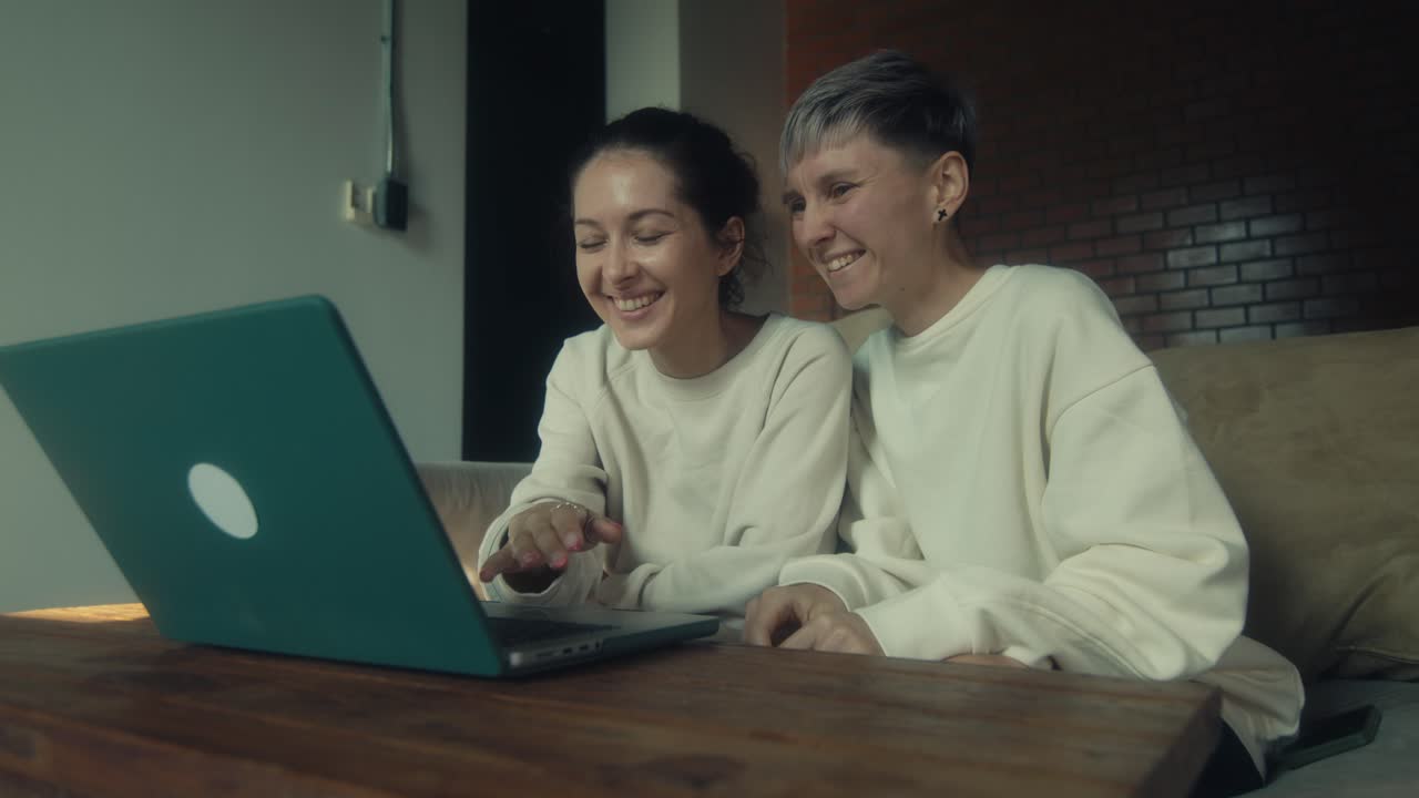 Two women laughing together at a laptop