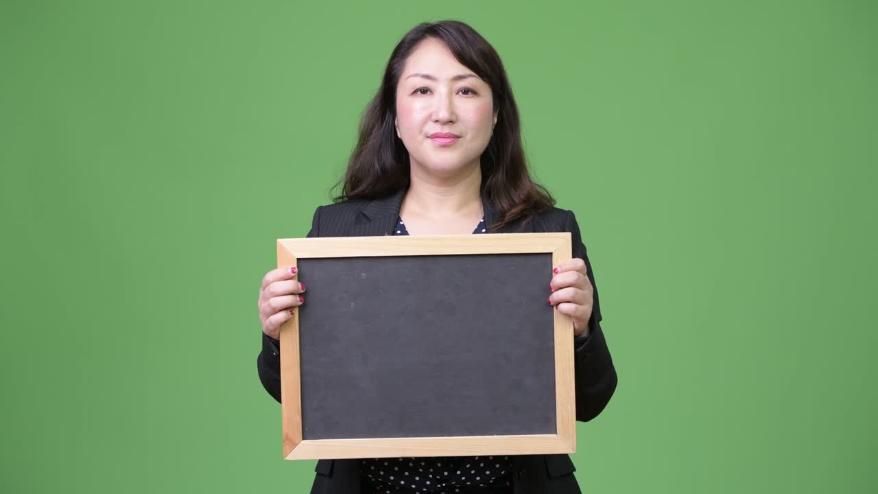 성숙하고 아름다운 아시아 사업가 여성이 블랙보드를 보여주고 있습니다.