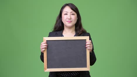 mature beautiful asian businesswoman showing blackboard