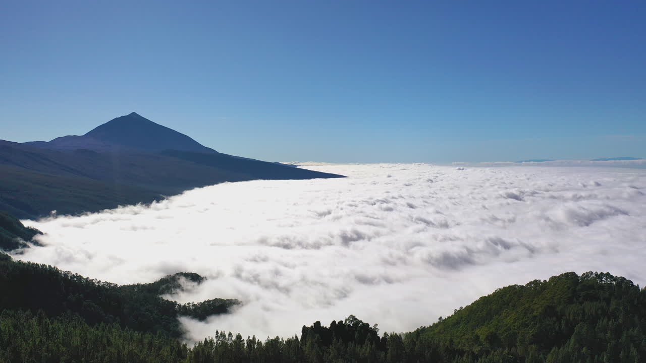 화창한 날 피코 데 테이데 산과 산비탈에 있는 숲의 숨막히는 전망과 아래 그란 카나리아 해안의 빽빽한 구름 반전