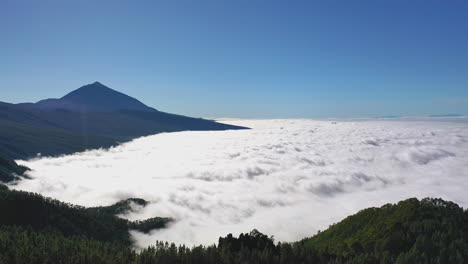 breathtaking view on the pico de teide mountain and the forests on the mountainside on a sunny day with a dense cloud inversion on the coast of gran canaria below