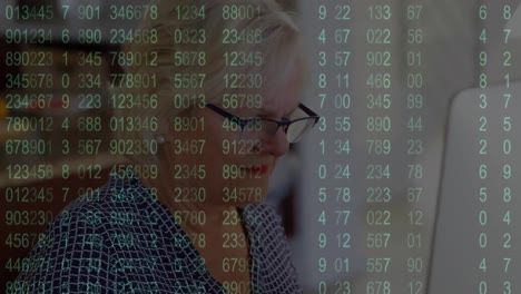 animation of increasing numbers over senior caucasian woman working on desktop