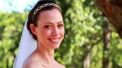 novia con un ramo de flores en el parque sonriendo a la cámara