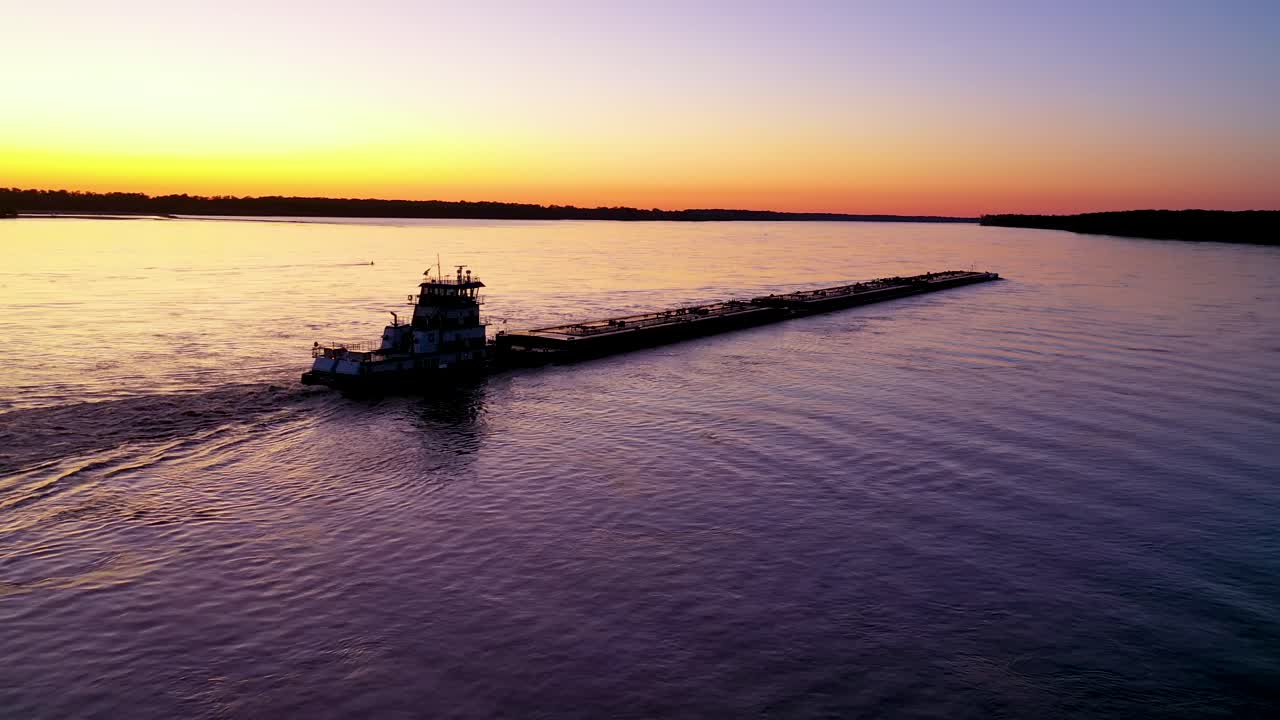 muy buena antena de un remolcador empujando una barcaza por el río mississippi, cerca de memphis, tennessee, al atardecer