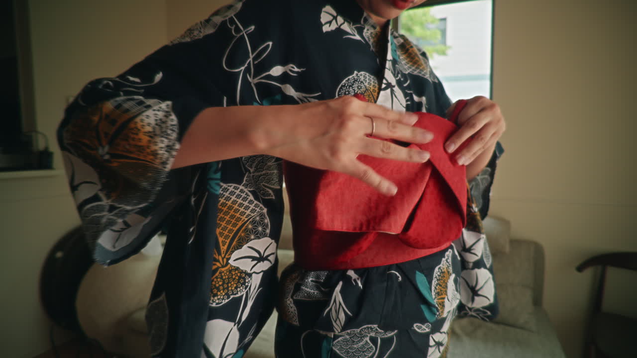 Woman wearing a yukata and tying an obi