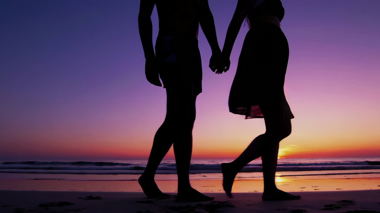 해가 지는 동안 해변을 고 있는 부부